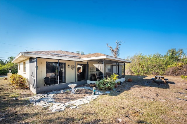 rear view of house featuring a yard and a sunroom