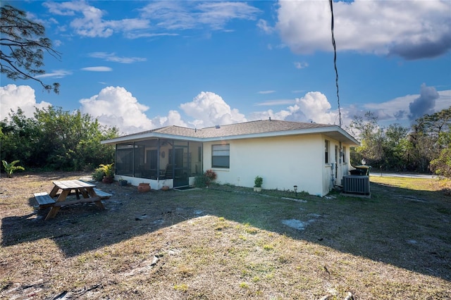 rear view of house featuring central AC, a yard, and a sunroom