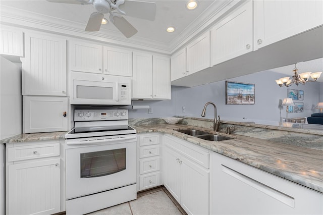 kitchen with light stone counters, white appliances, white cabinets, and a sink