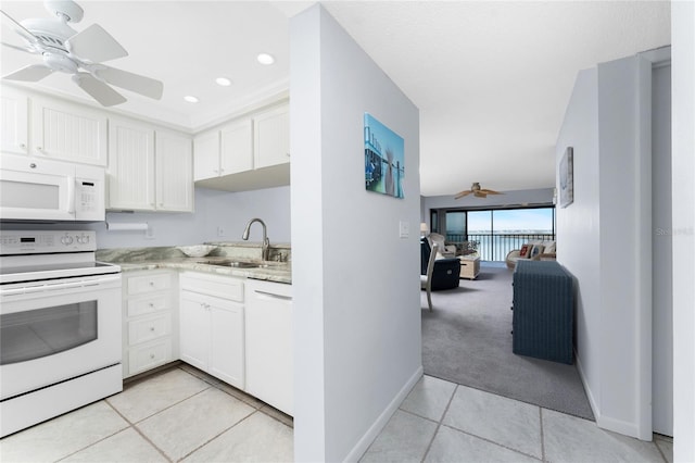 kitchen featuring light carpet, white appliances, light tile patterned floors, white cabinetry, and a sink