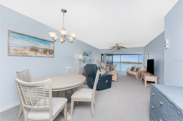 dining space with baseboards, vaulted ceiling, a textured ceiling, carpet flooring, and ceiling fan with notable chandelier