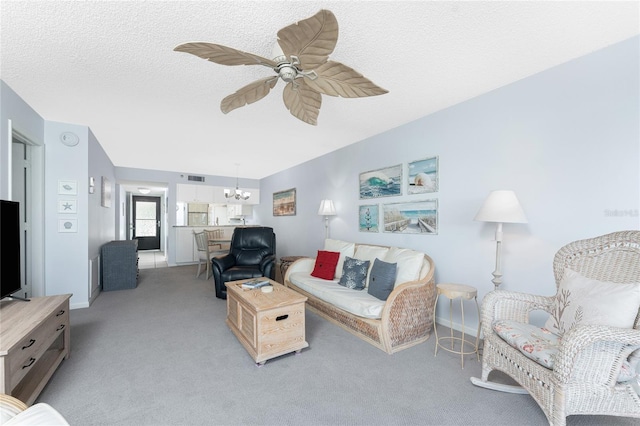 living area with visible vents, light carpet, a textured ceiling, and ceiling fan with notable chandelier