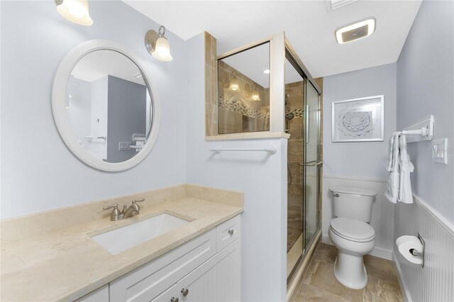 bathroom with a stall shower, visible vents, toilet, a wainscoted wall, and vanity