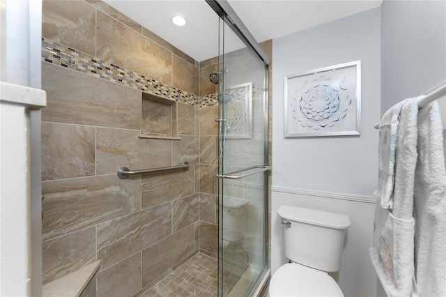 bathroom featuring toilet, a stall shower, recessed lighting, and wainscoting