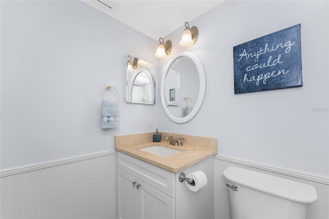 half bath featuring wainscoting, vanity, and toilet