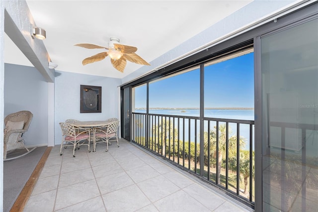 sunroom / solarium with a water view, ceiling fan, and a wealth of natural light