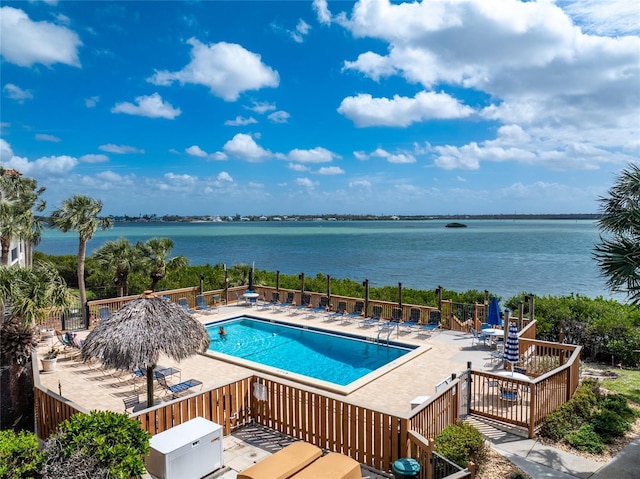 pool with a water view, fence, and a patio