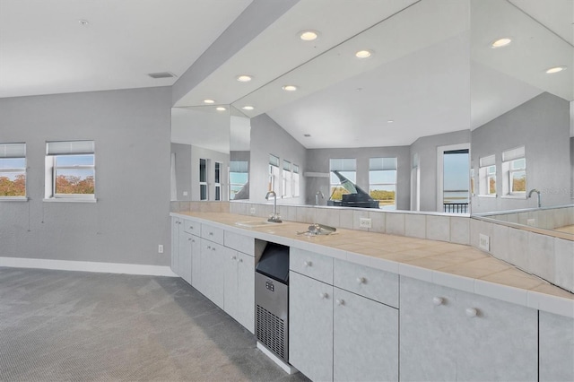 kitchen featuring tile countertops, lofted ceiling, sink, white cabinets, and dark carpet