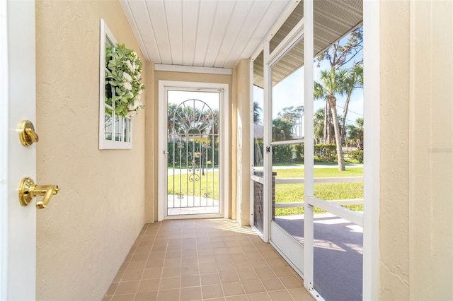 doorway to outside with tile patterned flooring, a wealth of natural light, and a textured wall