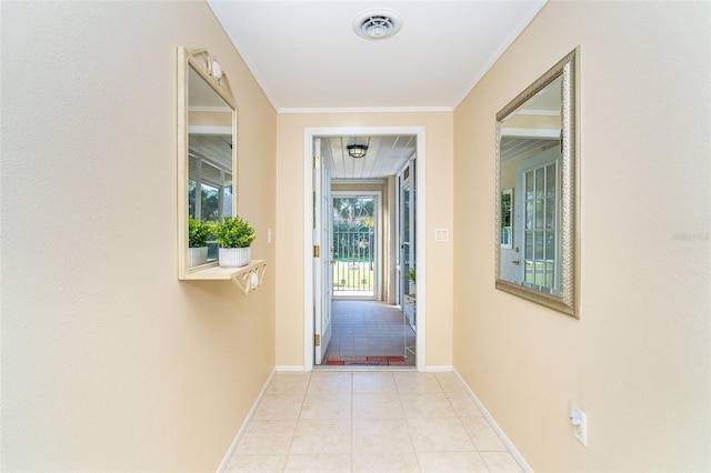 doorway to outside featuring ornamental molding, light tile patterned flooring, visible vents, and baseboards