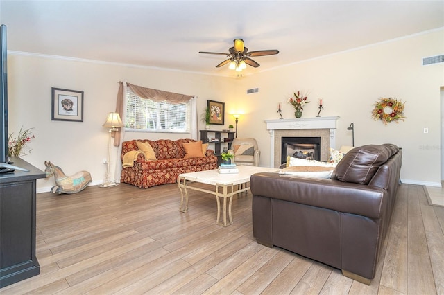 living room with crown molding, visible vents, and light wood-style floors