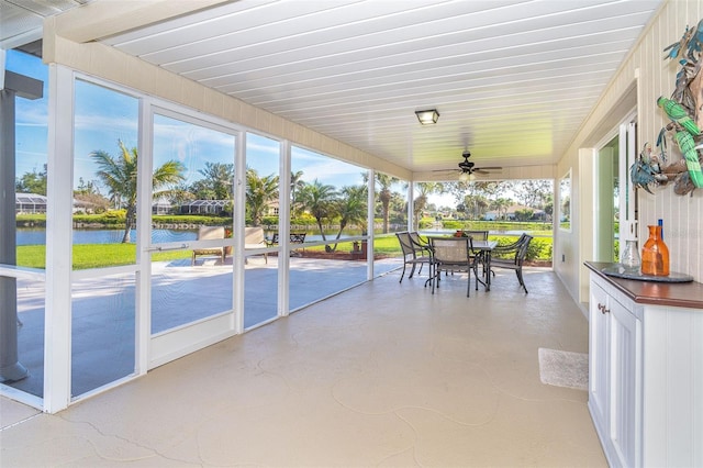 sunroom with a water view and ceiling fan