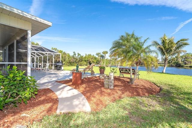 view of yard featuring a patio area, glass enclosure, and a water view