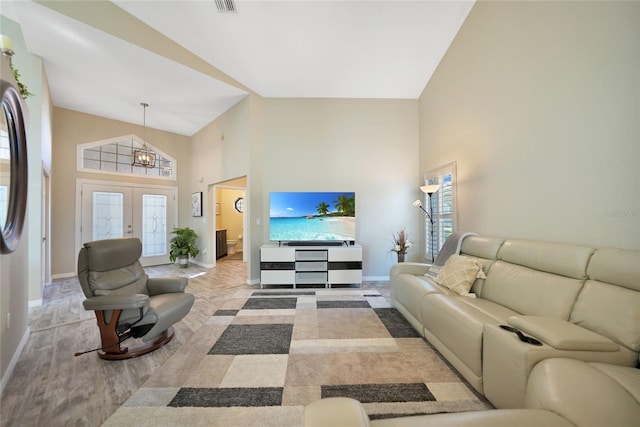 living room featuring light hardwood / wood-style floors, french doors, and a high ceiling