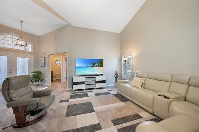 living room with a healthy amount of sunlight, a notable chandelier, high vaulted ceiling, and french doors