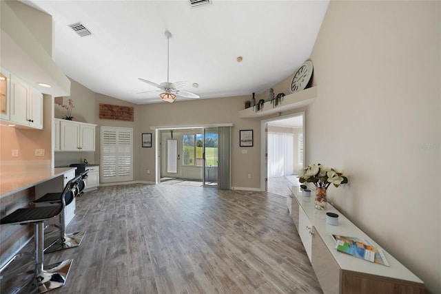 interior space with ceiling fan, built in desk, light wood-type flooring, and white cabinets