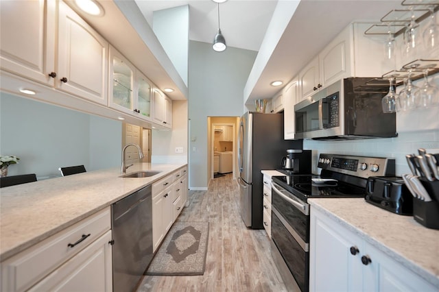 kitchen featuring white cabinetry, sink, decorative light fixtures, and appliances with stainless steel finishes