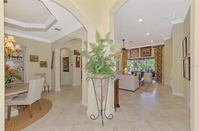 interior space with a raised ceiling, crown molding, and light tile patterned floors