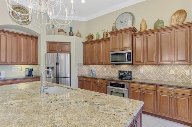 kitchen with appliances with stainless steel finishes, light stone countertops, and sink