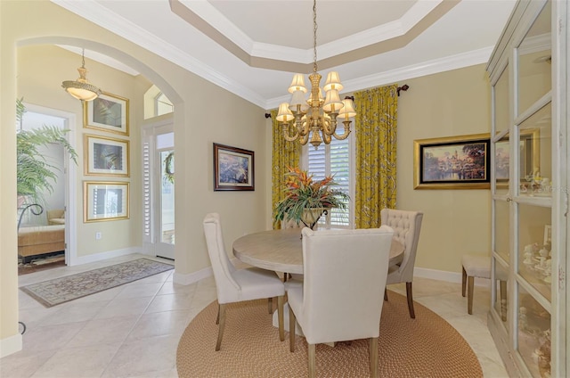 tiled dining area with a raised ceiling, crown molding, and a chandelier