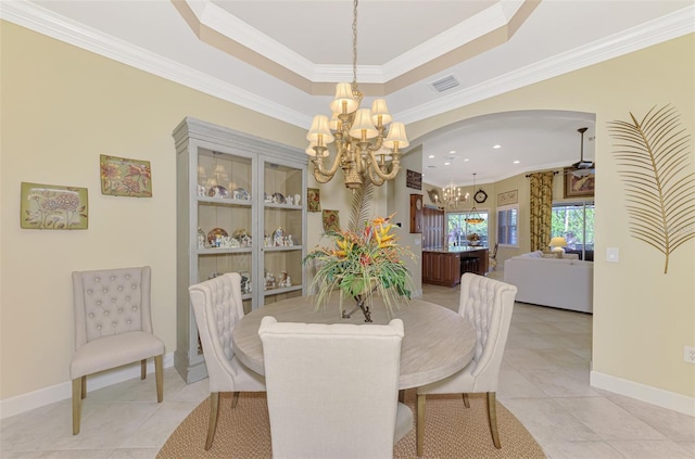 tiled dining area with an inviting chandelier, ornamental molding, and a raised ceiling