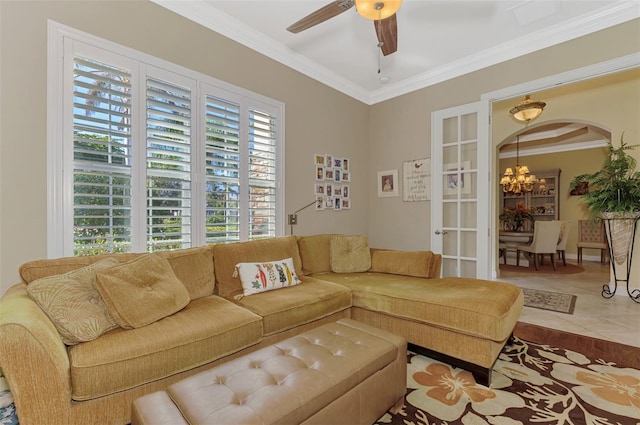 living room with tile patterned floors, ornamental molding, and ceiling fan with notable chandelier