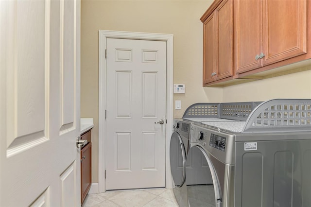 washroom featuring cabinets, washing machine and dryer, and light tile patterned flooring