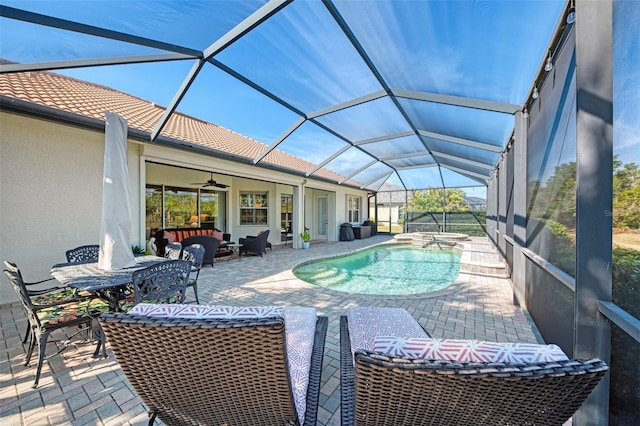 view of swimming pool featuring ceiling fan, glass enclosure, a patio area, and a hot tub