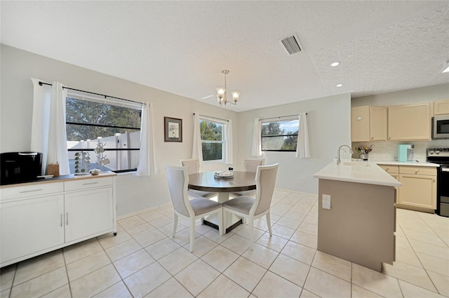 dining space with light tile patterned flooring, an inviting chandelier, sink, and a textured ceiling