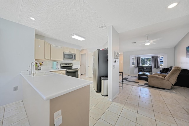 kitchen featuring light tile patterned flooring, sink, ceiling fan, kitchen peninsula, and stainless steel appliances