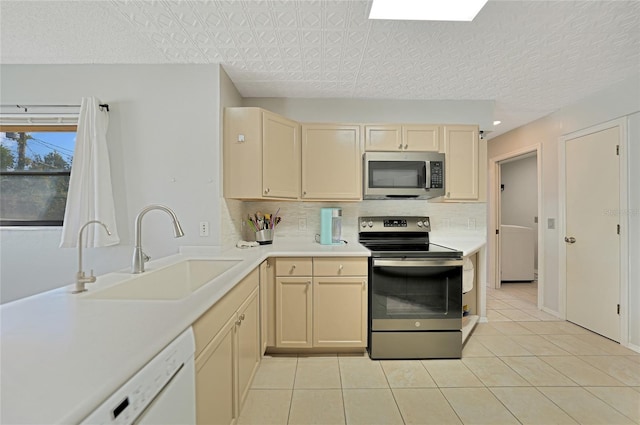 kitchen with sink, light tile patterned floors, a textured ceiling, and appliances with stainless steel finishes