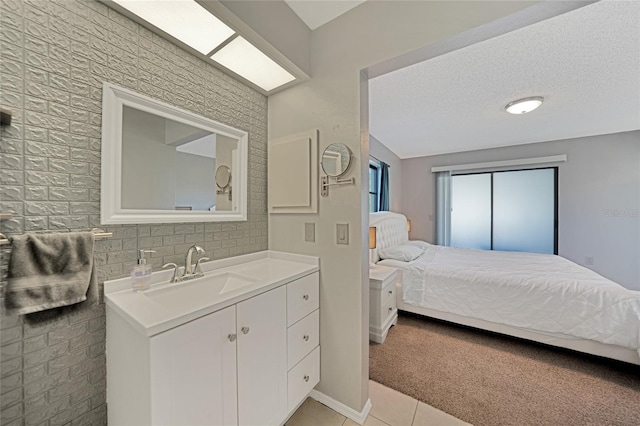 tiled bedroom with sink and a textured ceiling