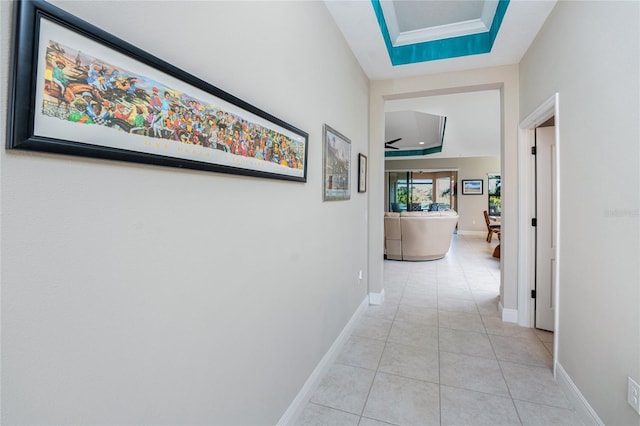 hall featuring a raised ceiling and light tile patterned floors