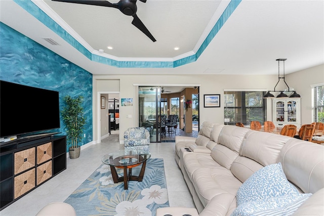 living room featuring ornamental molding, a raised ceiling, and ceiling fan