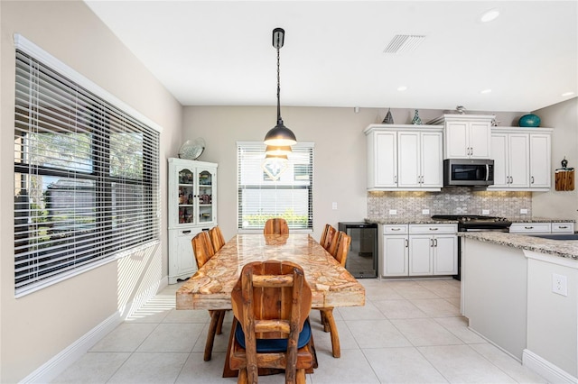 dining space with plenty of natural light, light tile patterned floors, and beverage cooler