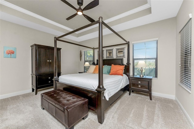 carpeted bedroom with multiple windows, crown molding, a raised ceiling, and ceiling fan