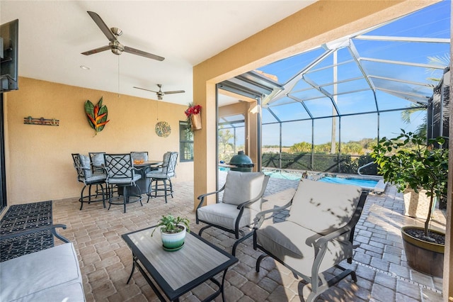 view of patio with an outdoor living space, ceiling fan, and glass enclosure