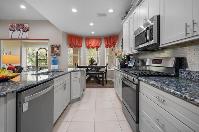 kitchen with sink, backsplash, white cabinets, and appliances with stainless steel finishes