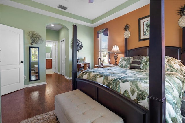 bedroom with ceiling fan, ensuite bathroom, and dark hardwood / wood-style floors