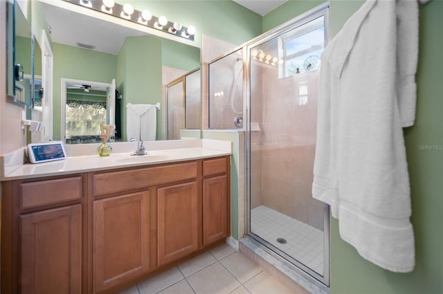 bathroom with a shower with door, vanity, and tile patterned floors