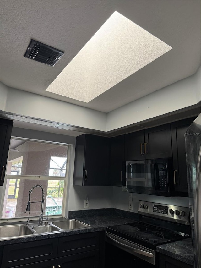 kitchen with stainless steel range with electric stovetop, sink, and a textured ceiling