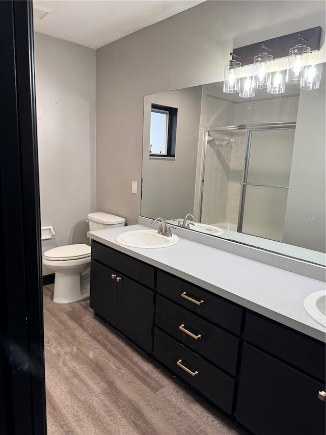 bathroom with vanity, hardwood / wood-style flooring, a shower with shower door, and toilet