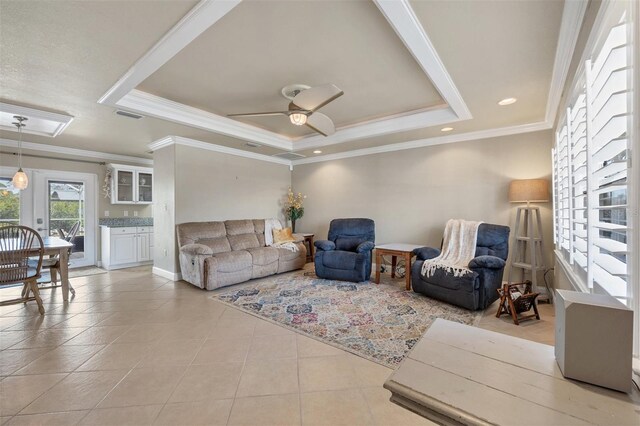 tiled living room with ornamental molding, ceiling fan, and a tray ceiling