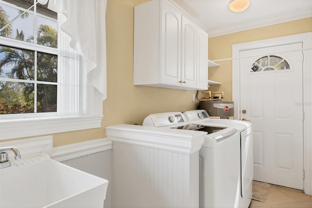 laundry room with water heater, sink, crown molding, cabinets, and washing machine and dryer