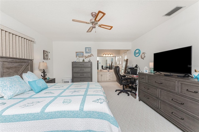 carpeted bedroom with ensuite bath and ceiling fan