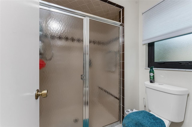 bathroom featuring toilet and a shower with shower door