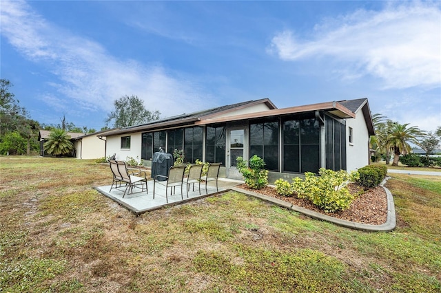 back of house featuring a sunroom, a patio area, and a lawn