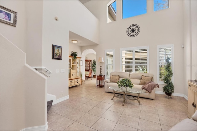 interior space featuring light tile patterned floors, baseboards, arched walkways, and a wealth of natural light