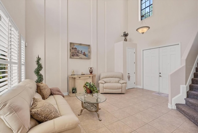 living area with a towering ceiling, baseboards, stairway, and light tile patterned flooring