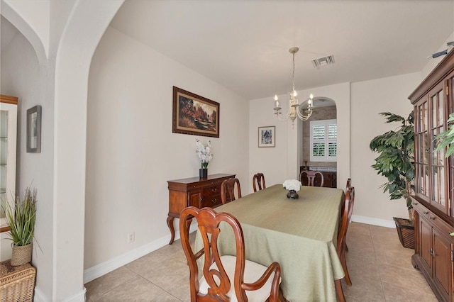 dining room featuring light tile patterned floors, visible vents, a chandelier, and arched walkways